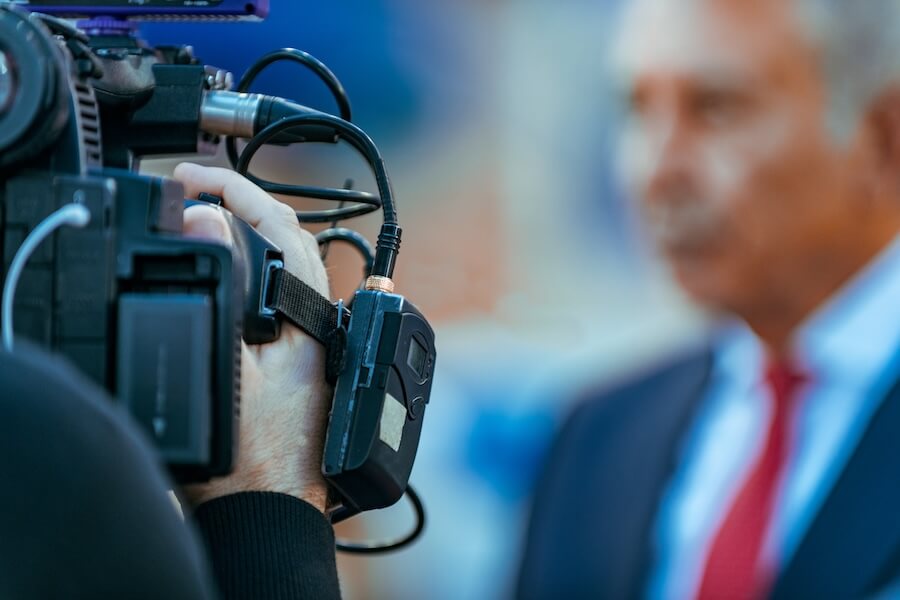 TV Azteca customer story: Cameraman filming interview with news anchor. Broadcasting.