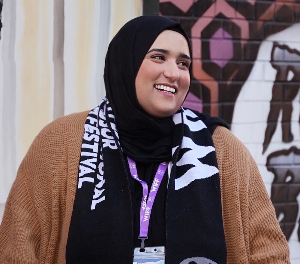 Nuha at WIFF. Smiling woman in hijab and festival scarf. Windsor International Film Festival. Nuha at WIFF. Smiling woman in hijab and festival scarf. Windsor International Film Festival.