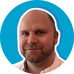 Headshot of Nick Long, smiling man with beard, set against a blue background.