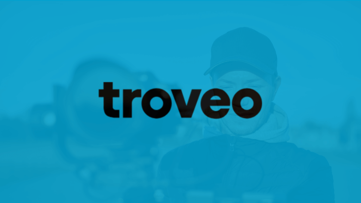 Troveo AI Customer Story: Troveo logo on a blue background with a blurred image of a person.